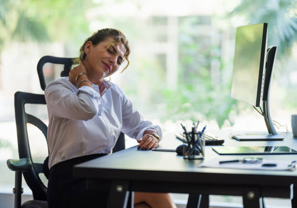 picture of woman sitting at a desk in pain holding her neck